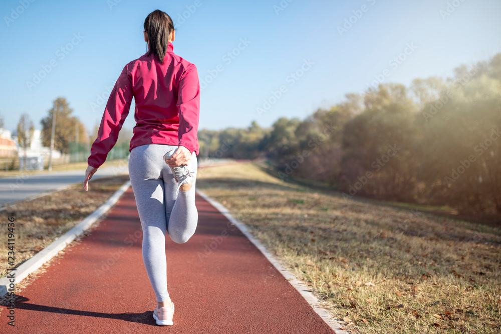 Young fitness woman runner stretching legs before workout. Woman runner.