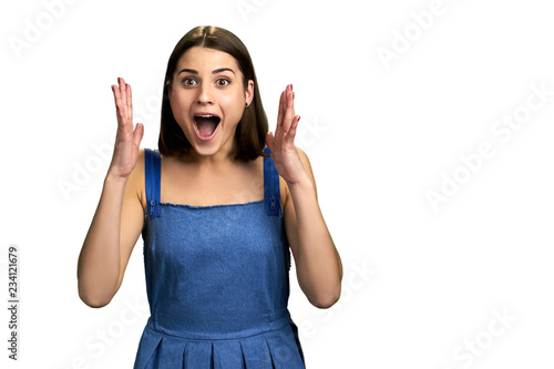 Happy excited woman gesturing with hands. Portrait of a joyful girl standing with open mouth and with raised hands, copy space.