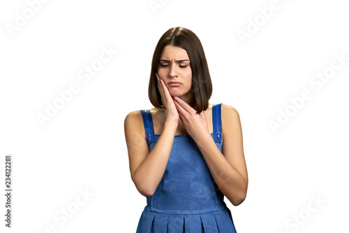 Young woman having strong teeth pain. Beautiful upset girl suffering from tooth ache over white background. Tooth pain and dentistry.