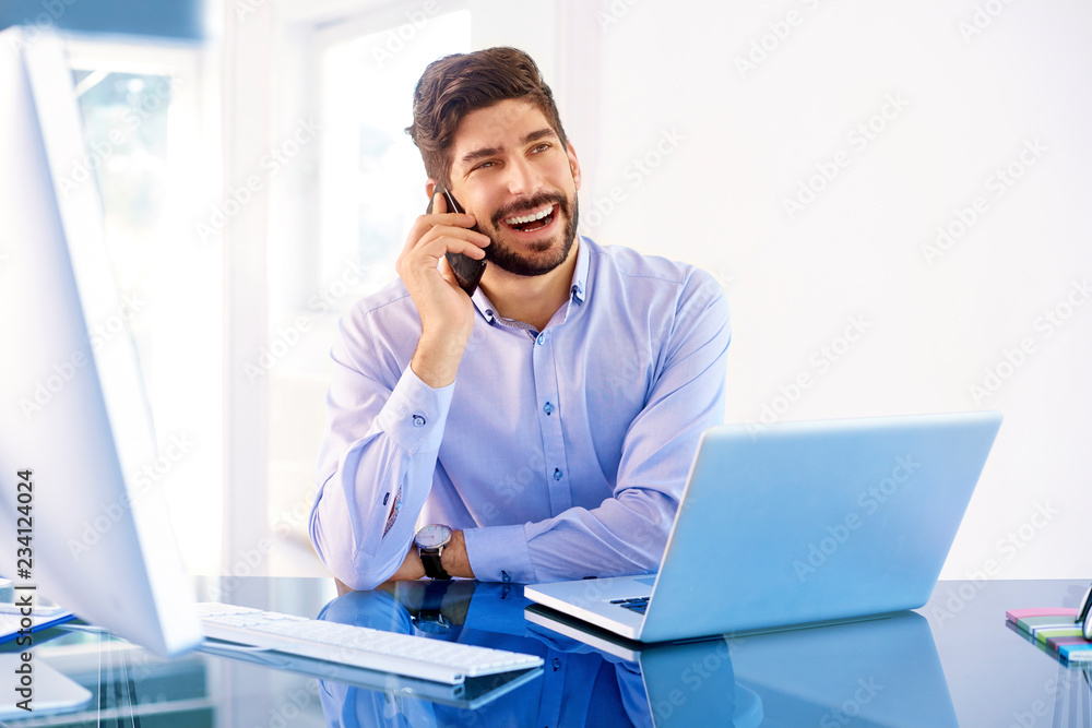 Young businessman making a call while working on laptop Young businessman making a call while working on laptop