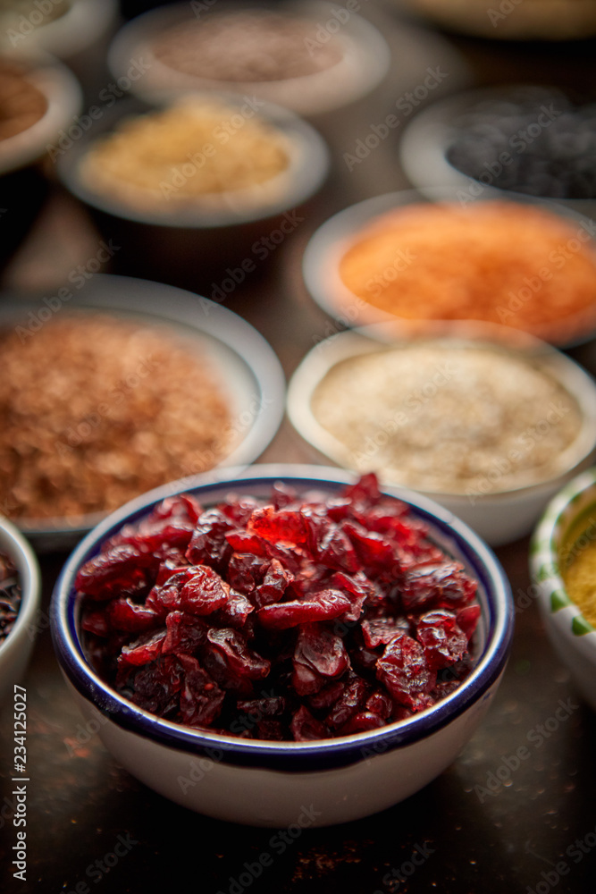 Dry cranberries in ceramic bowl. Composition of superfoods in background. Placed on dark rusty table. Selective focus. Dry cranberries in ceramic bowl. Composition of superfoods in background. Placed on dark rusty table. Selective focus.