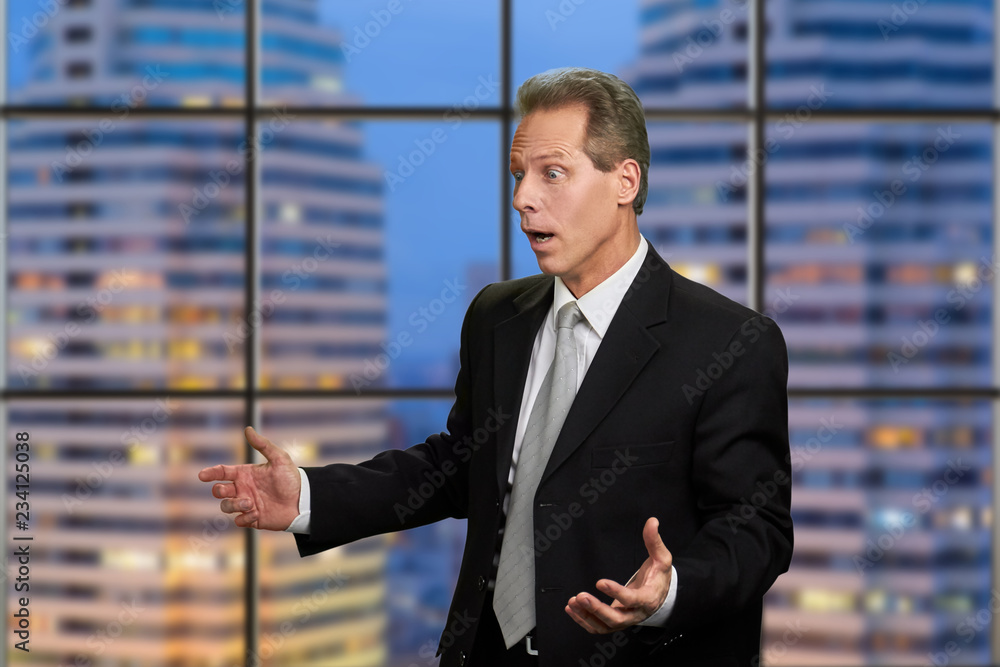 Portrait of surprised middle-aged businessman. Man in business suit looking shocked on skyscraper background. Human expressions of surprise.