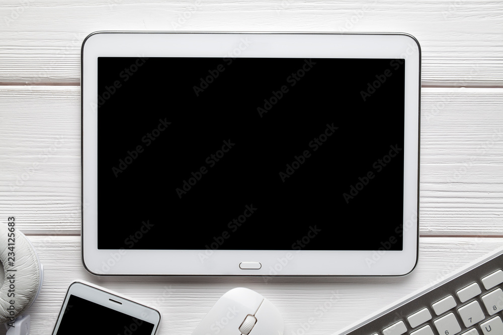 White modern digital tablet and other electronics accessories on wooden table White modern digital tablet and other electronics accessories on wooden table