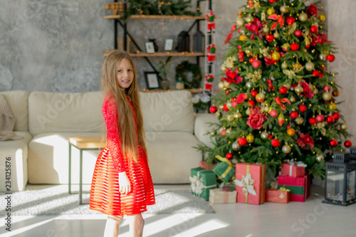 Beautiful girl near the Christmas tree with gifts