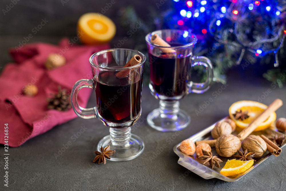 Red mulled wine in glasses with electric lights at dark background