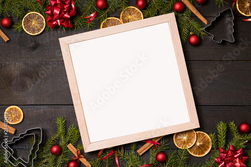 Empty  white  clear frame on dark rustic wood background with Christmas decoration and fir branch frame. Top view with free text copy space