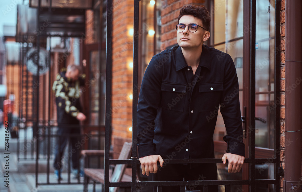A young handsome man standing near a cafe outdoors. A young handsome man standing near a cafe outdoors.