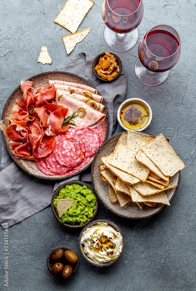Antipasto. Meat platter, chips and sauces, red wine on gray background. Top view Antipasto. Meat platter, chips and sauces, red wine on gray background. Top view