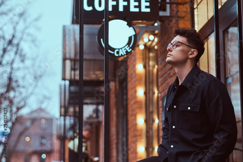 Photography A young handsome man standing near a cafe outdoors.