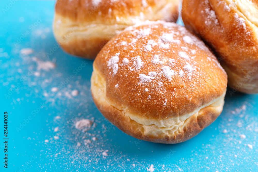 Tasty sweet donuts with powdered sugar on bright blue background