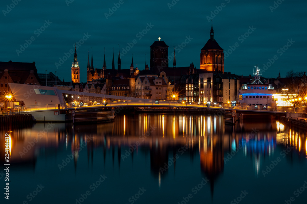 Widok na miasto Gdańsk od strony kładki na Ołowiance, stare miasto nocą. 