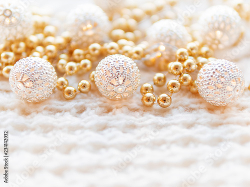 Christmas and New Year decorations on white knitted background. Metal light bulbs with delicate pattern, golden beads.