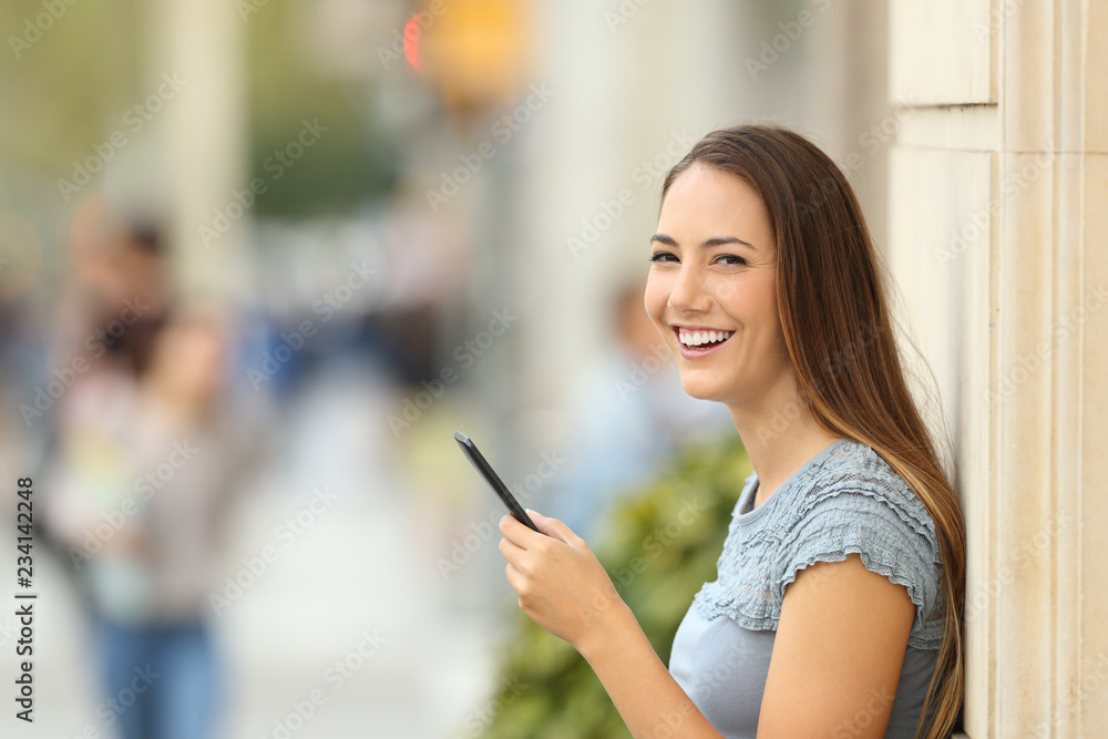 Girl using a smart phone on the street looking at you Girl using a smart phone on the street looking at you