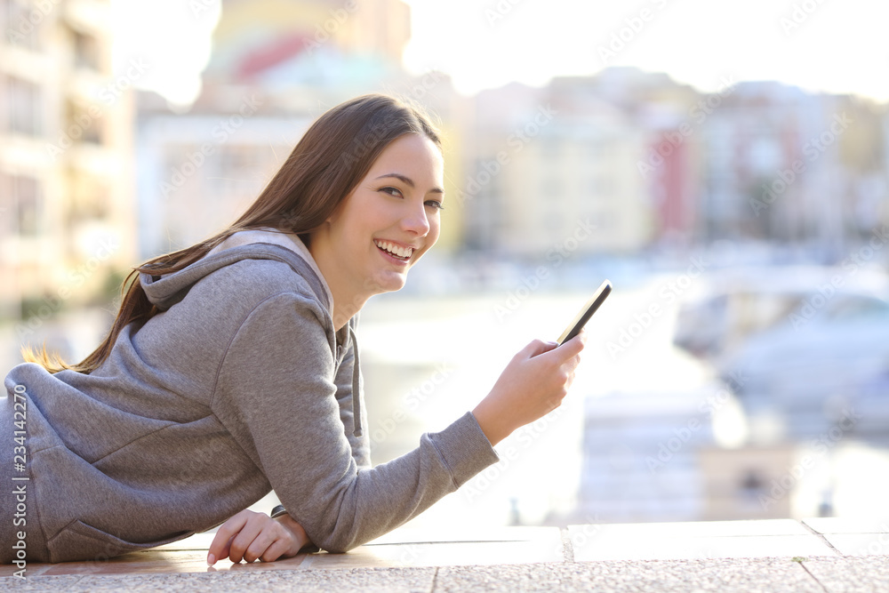 Happy teen holding phone looking at camera