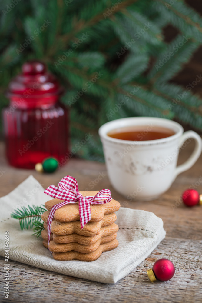 A pile of gingerbread Christmas cookies onbeige napkin with a cup of tea