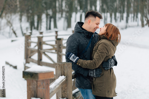 Winter portrait of young beautiful happy smiling couple outdoors. Christmas and winter holidays. Man and woman in snowy park