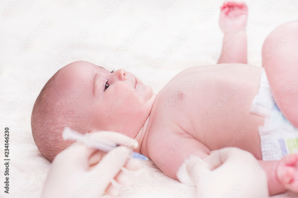 A very small child, a baby, is lying in the doctor's office and the doctor makes an injection. A very small child, a baby, is lying in the doctor's office and the doctor makes an injection.