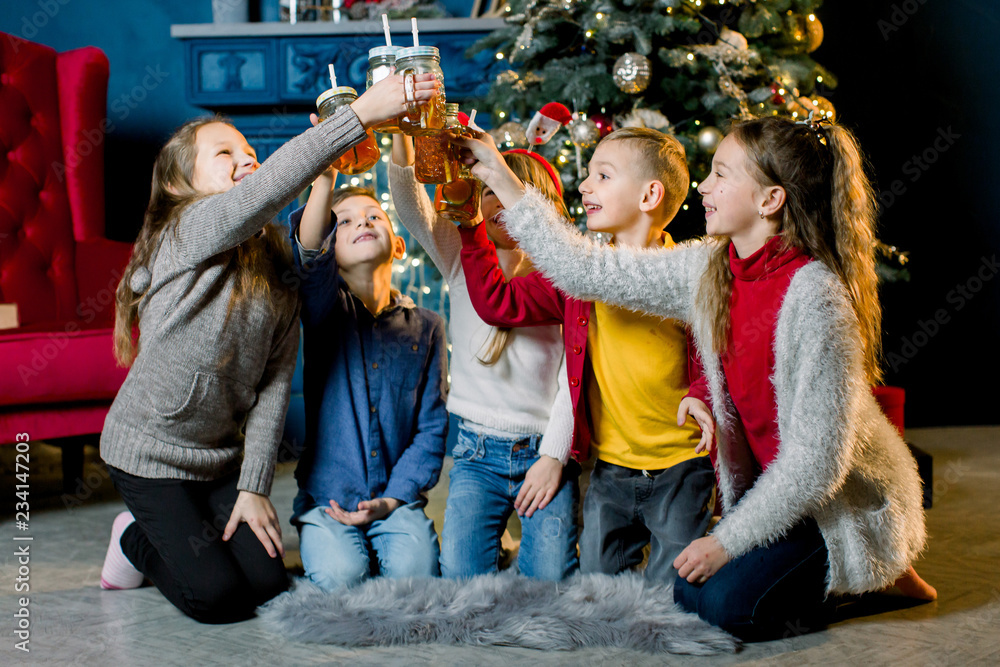 Merry Christmas! A group of children on the background of a Christmas tree, drinking lemonade and knocking glasses