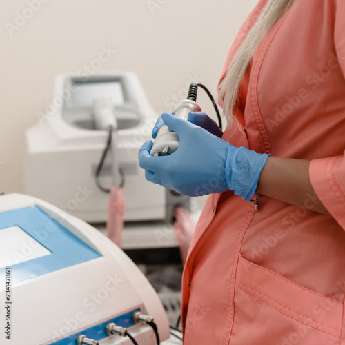 Closeup of cosmetologist's hand pressing button on modern laser machine