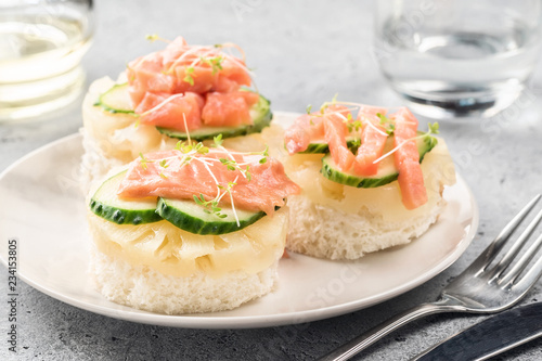 Bruschetta toast of white bread with slices of pineapple cucumber fish salmon fresh green sprouts