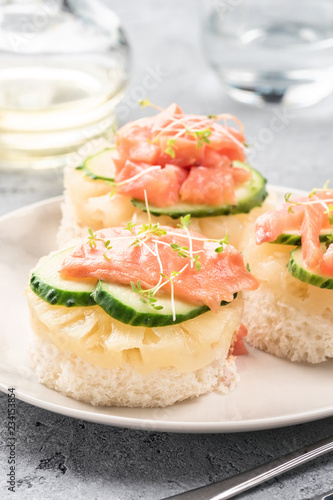 Bruschetta toast of white bread with slices of pineapple cucumber fish salmon fresh green sprouts