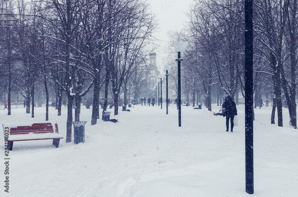 People walking along a city alley during a snowfall in winter People walking along a city alley during a snowfall in winter