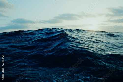 Fototapeta view of a large wave far out at the ocean from a sailboat
