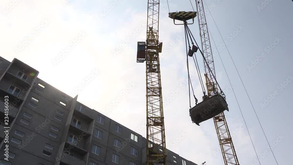 Construction site, crane lifting wall panel. Crane lifts heavy load on