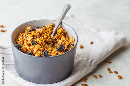 Baked granola with raisins in gray bowl.