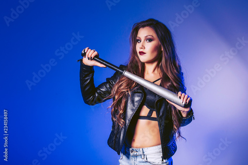 A beautiful girl is holding a baseball bat. Shooting in the studio