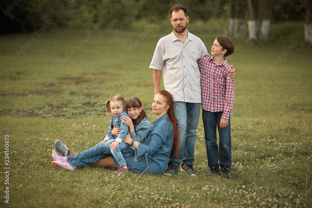 a family of five in the summer in the Park. bearded man and his wife with red hair with three children. happy family.