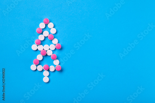 Conceptual background on the medical theme for the new year and Christmas, a Christmas tree of white pills decorated with red pills top view with space for text.