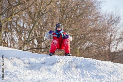 boy at the sledge on top of snowy hill waiting for riding