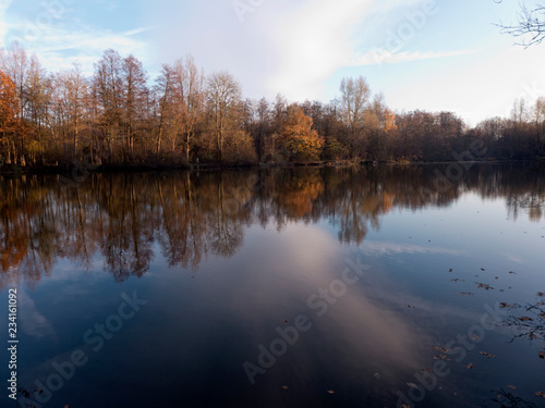 Spaziergang im Herbst entlang eines kleinen Sees in Bünde Deutschland. Wunderschöne Spiegelungen der Bäume im Wasser.