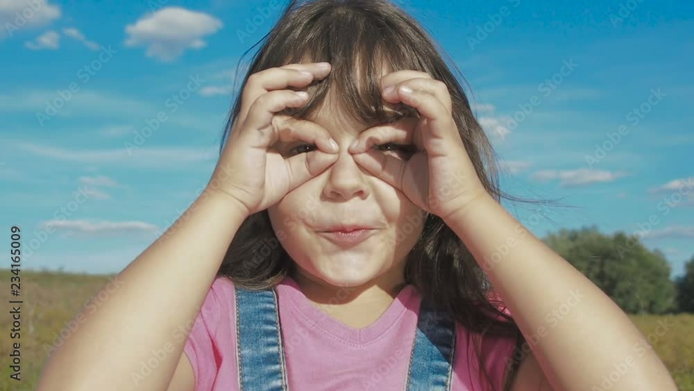 Child makes glasses with hands. Funny little girl makes glasses with her hands. Child makes glasses with hands. Funny little girl makes glasses with her hands.