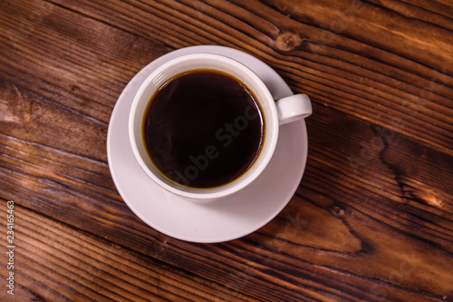 Cup of dark coffee on wooden table. Top view