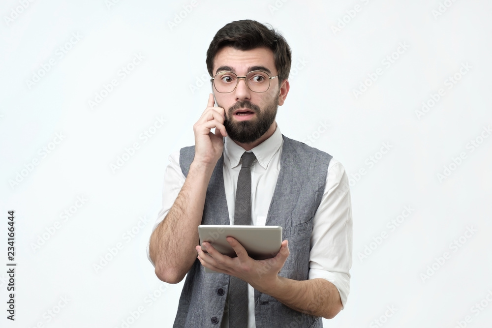 Hispanic guy with beard talking on a mobile phone trying to find solution from financial problems Hispanic guy with beard talking on a mobile phone trying to find solution from financial problems