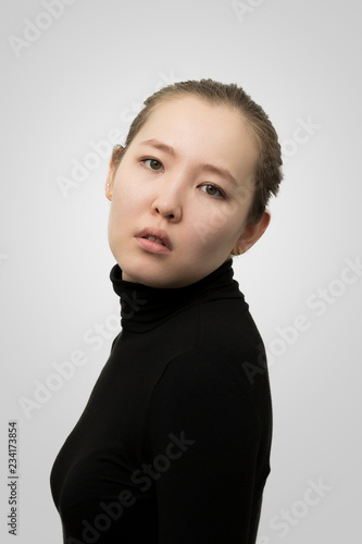 Asian female model on gray gradient background. Mongolian young woman wears a black turtleneck.