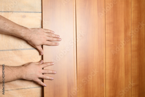 Male hands install MDF panels on the prepared wall