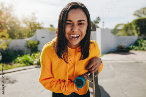 Excited teenage girl standing in street with her longboard