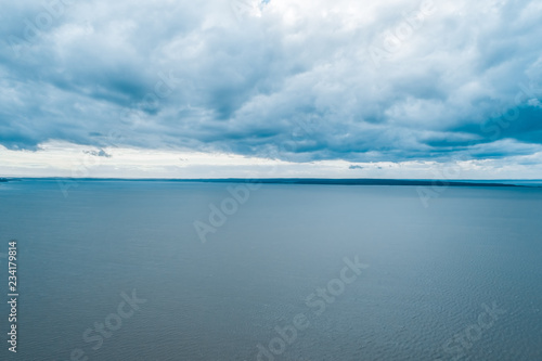 Aerial seascape - rain clouds over calm water and small patch of land on the horizon - tranquil overcast scene