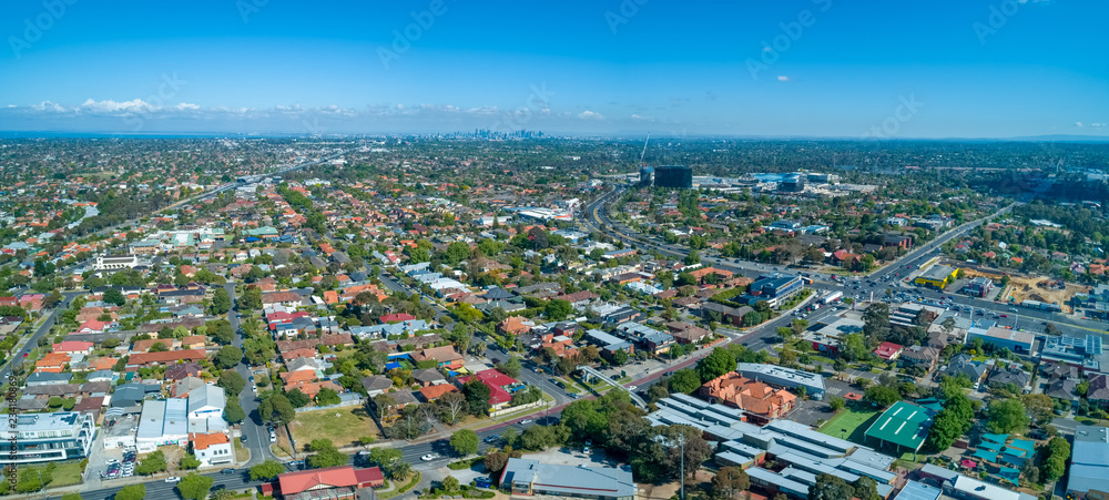 Wide aerial panorama of Oakleigh suburb with Melbourne CBD high rise buildings in the distance