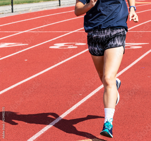 High school female running on a red track