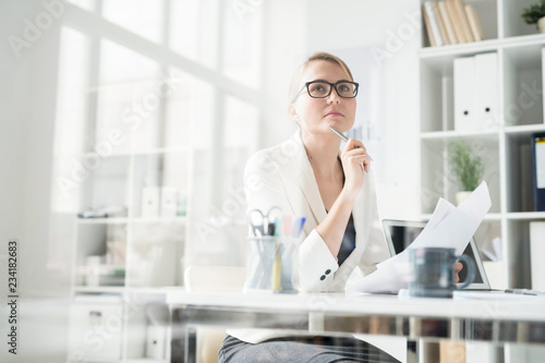 Принти на полотні Serious pensive attractive business lady in glasses sitting at table and thinkin