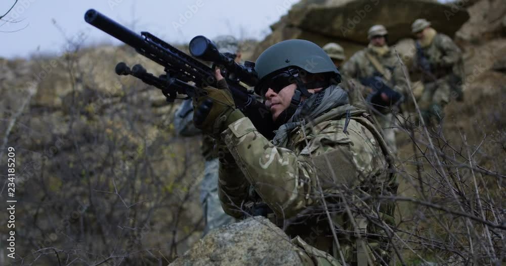 Medium slow motion shot of fully equipped and armed soldier providing cover during patrol Medium slow motion shot of fully equipped and armed soldier providing cover during patrol