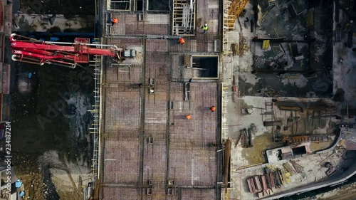 Aerial view of construction workers work on top of the building at construction site - Drone is rising up