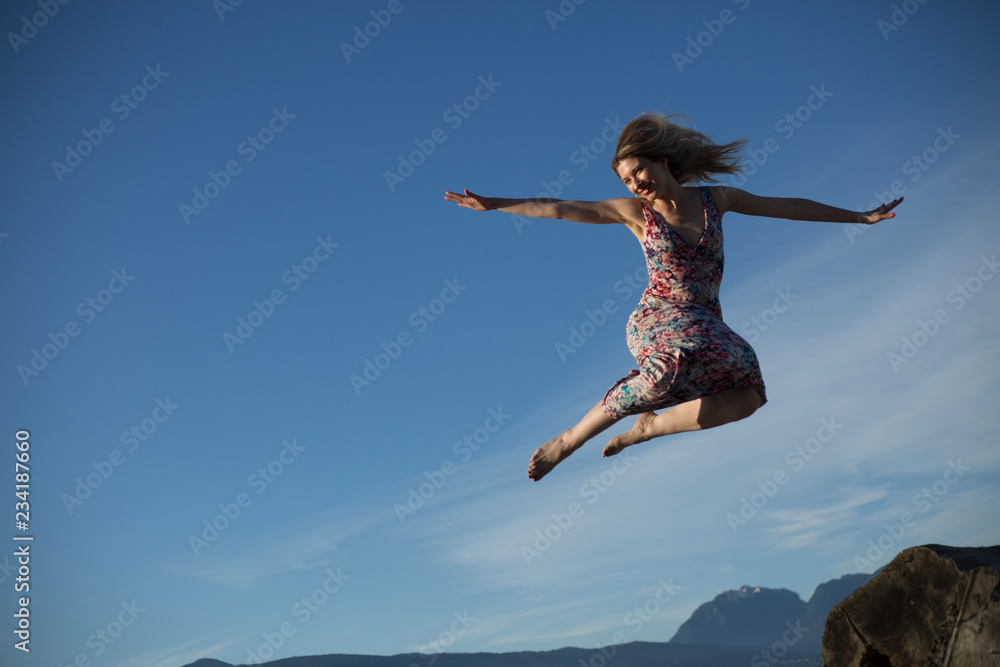 Conceptual positive mindset young woman jumping blue sky Conceptual positive mindset young woman jumping blue sky
