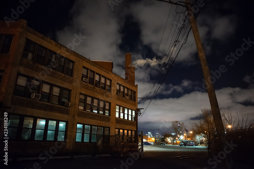 Scary industrial urban street city night scene with a vintage factory warehouse and smokestacks