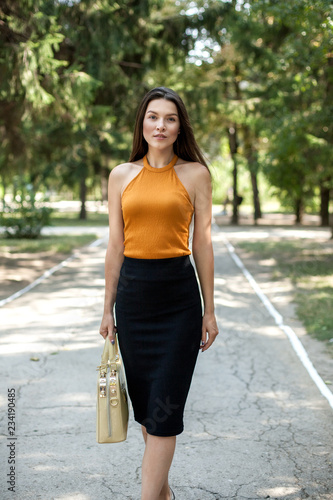 happy business woman with a bag in her hands in the park walking on the way. © tumskaia