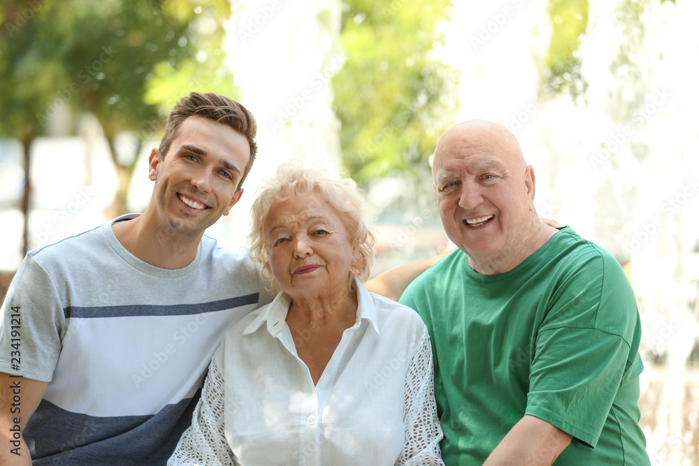 Man with elderly parents outdoors on sunny day